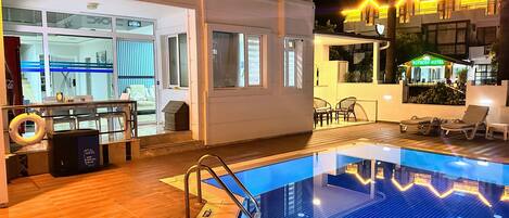 A swimming pool with a sunken seating area, a bar, and a view of the hotel interior.