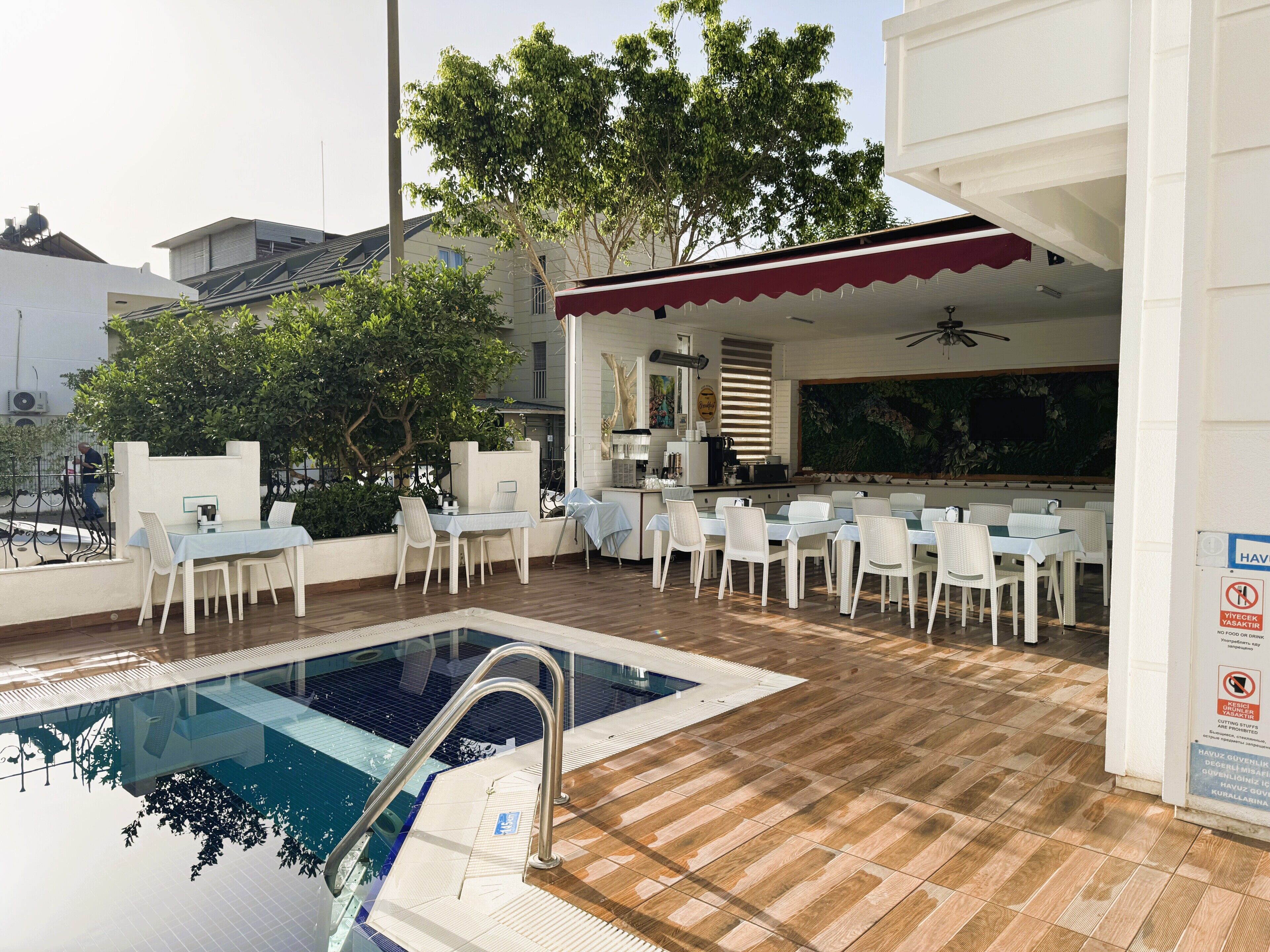 An outdoor pool area with a dining setup and a covered seating area.