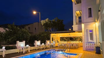 A swimming pool with lounge chairs and a bar area.
