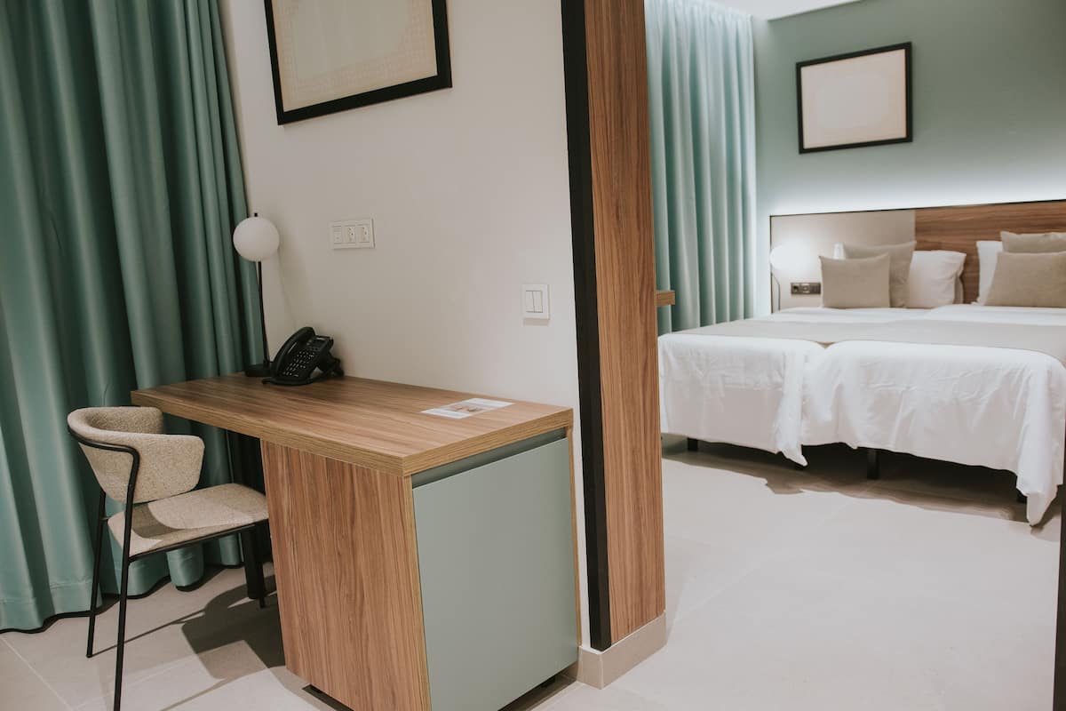 Une chambre d’hôtel équipée d’un bureau, d’une chaise et d’un lit avec deux oreillers.