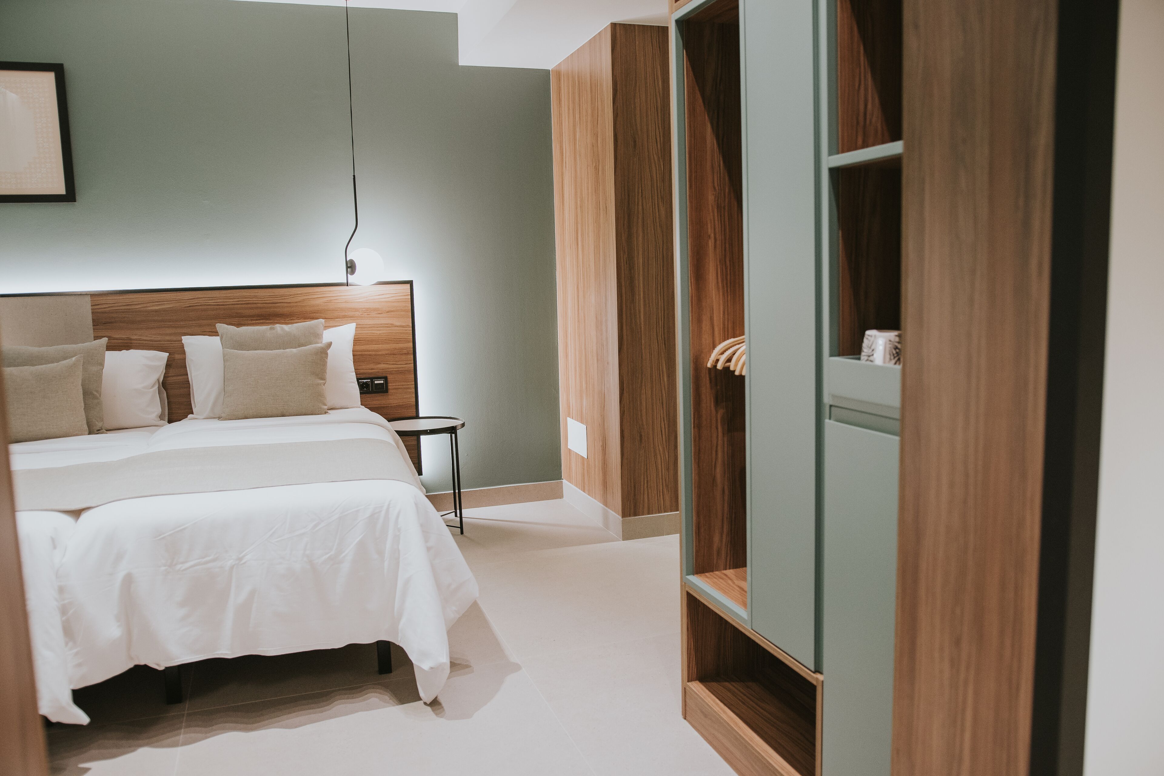 Un dormitorio moderno con una cama grande, una mesita de noche y un armario de madera.