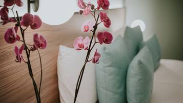 A bedroom with a bed, pillows, and an orchid plant.