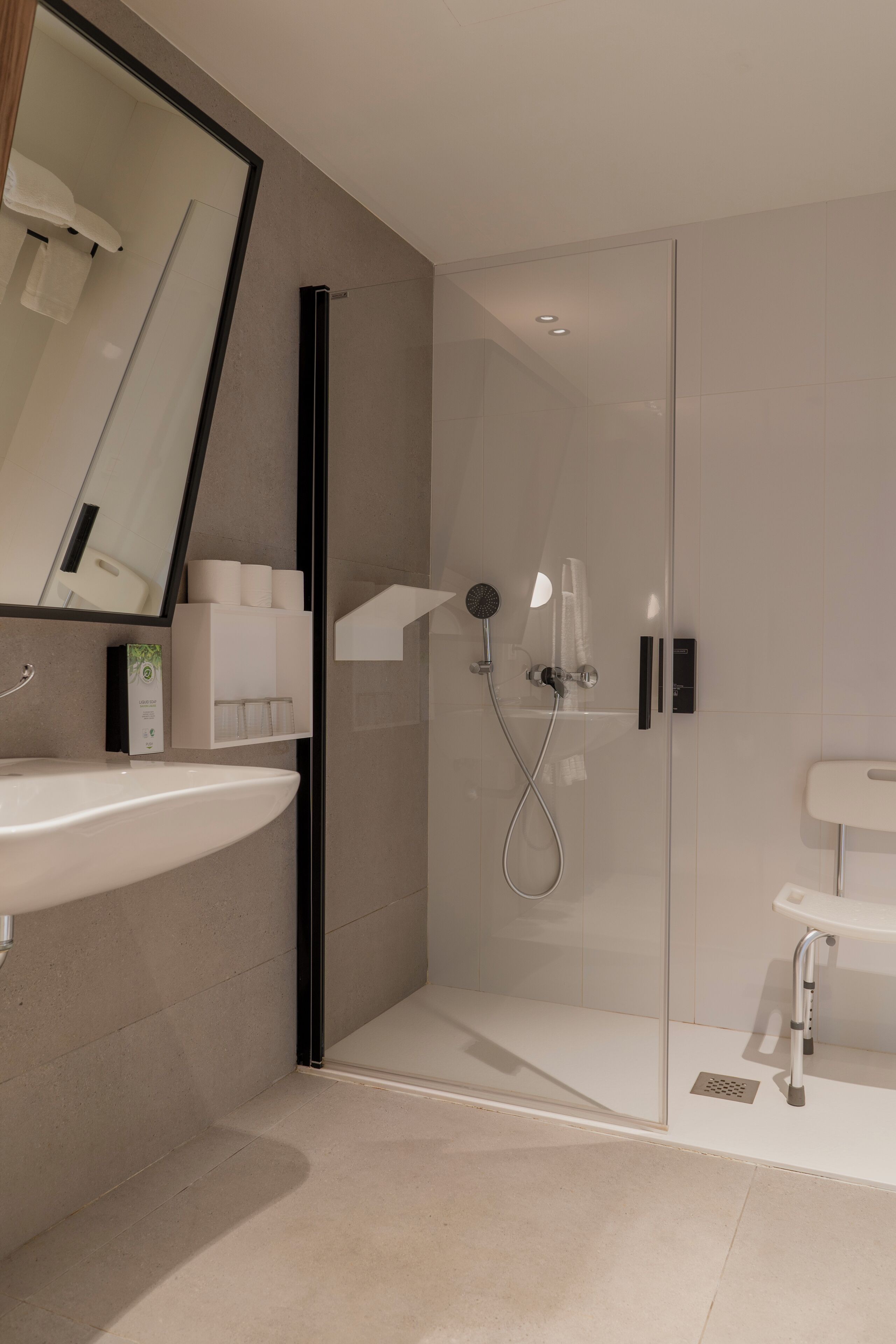 A modern bathroom with a glass-enclosed shower, a white sink, and a mirror.