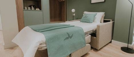 A bedroom with a bed, a wardrobe, a bedside table, and a floor lamp.