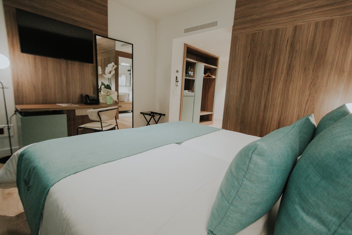 Une chambre d’hôtel comprenant un lit, un bureau, une chaise, un miroir et une armoire.