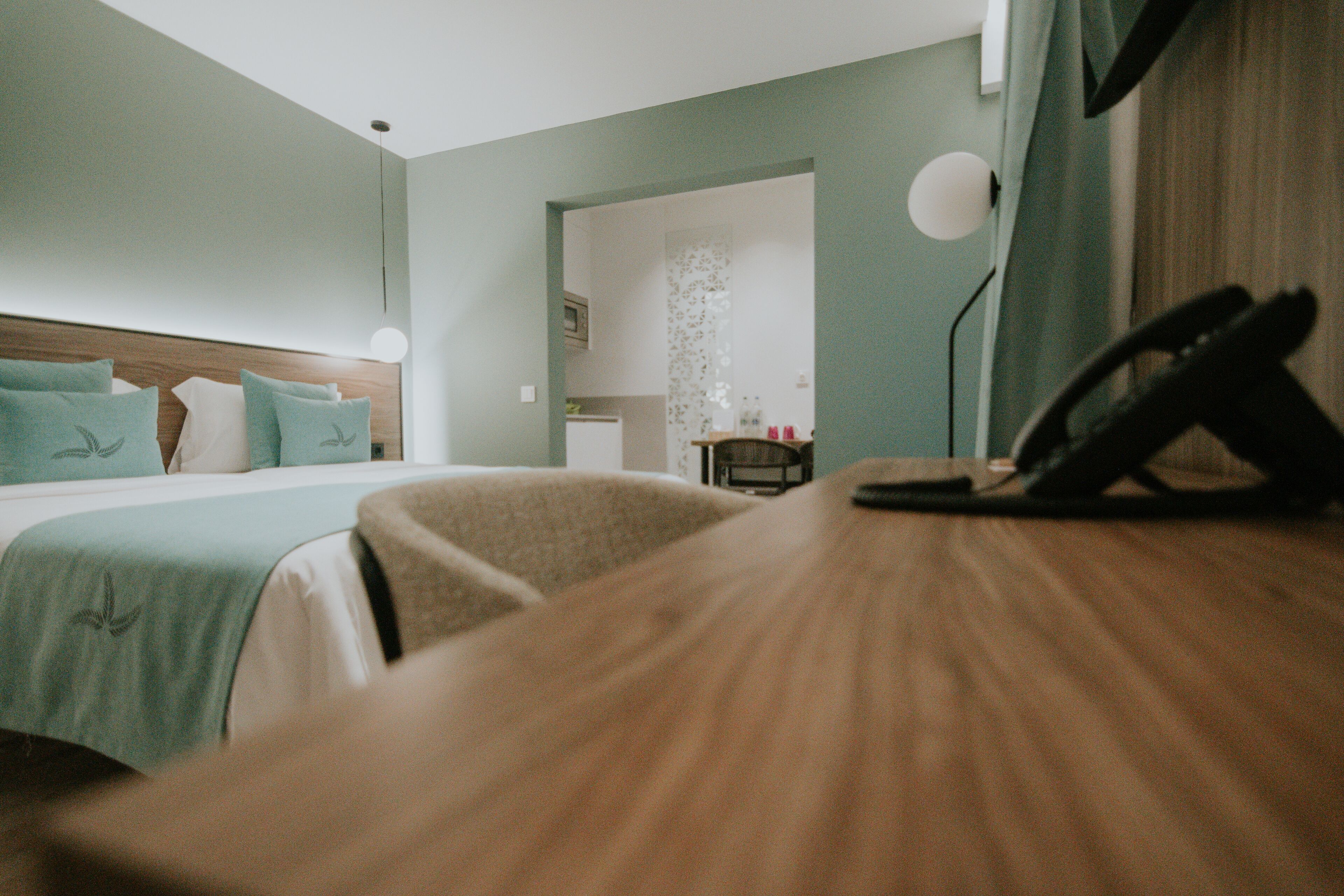 Habitación de hotel con cama, escritorio, teléfono y vistas al baño.