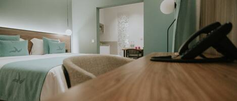 A hotel room with a bed, a desk, a telephone, and a view of the bathroom.