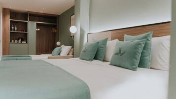 A hotel room with two beds, a wardrobe, a bedside table, and a lamp.