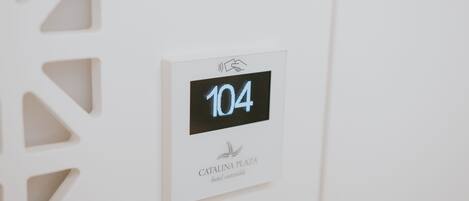 A digital display with the number 104, indicating room number or floor level, and the text "CATALINA PLAZA hotel sostenible" below it.