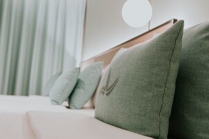A bed with green pillows and a round wall-mounted light.