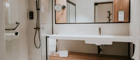 A modern bathroom with a glass-enclosed shower, a wooden vanity, and a large mirror.