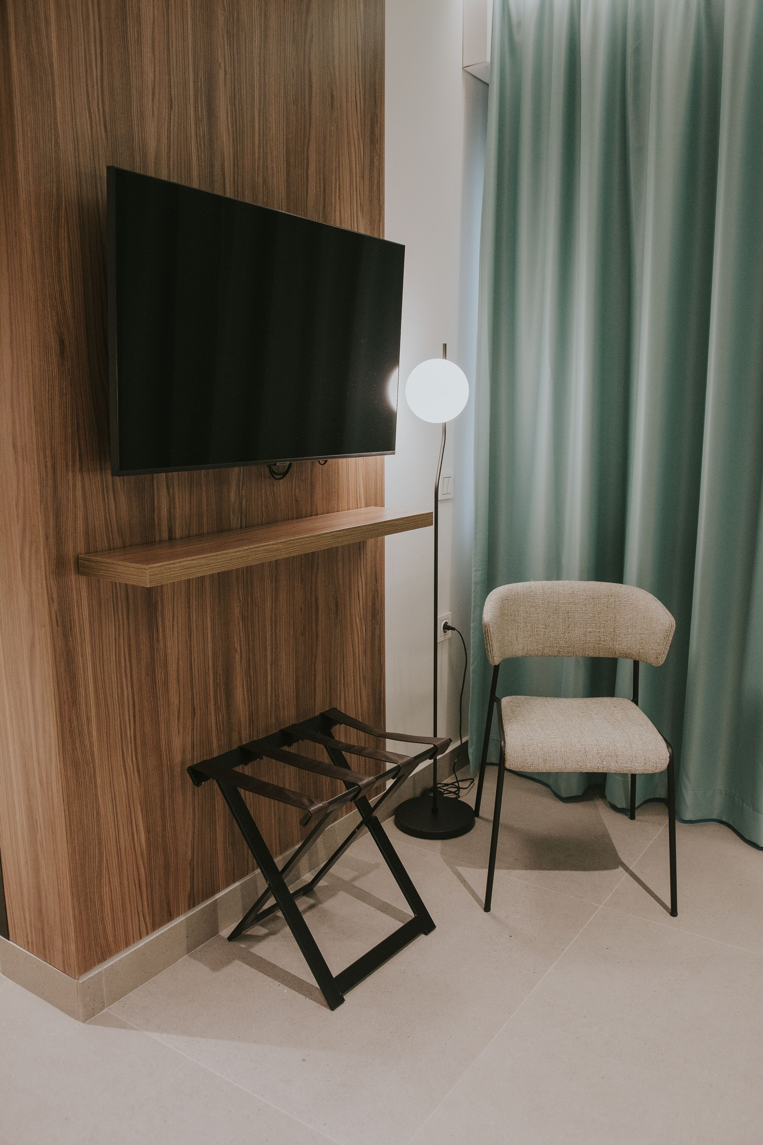 A modern room with a mounted TV, a standing lamp, and a chair.