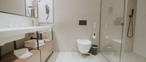 Un bagno moderno con doccia vetrata, un water bianco e un mobile lavabo con asciugamani.