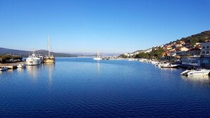 Uma marina com vários barcos atracados, céu claro e paisagem acidentada ao fundo.