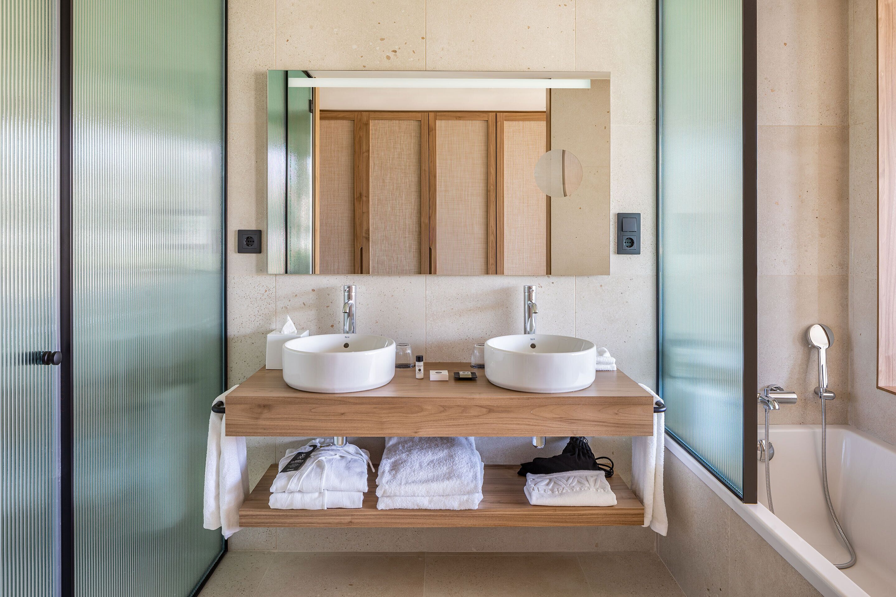 Een moderne badkamer met twee wastafels, een spiegel en een douche.