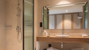 Un baño moderno con cabina de ducha de vidrio, tocador de madera y un espejo grande.