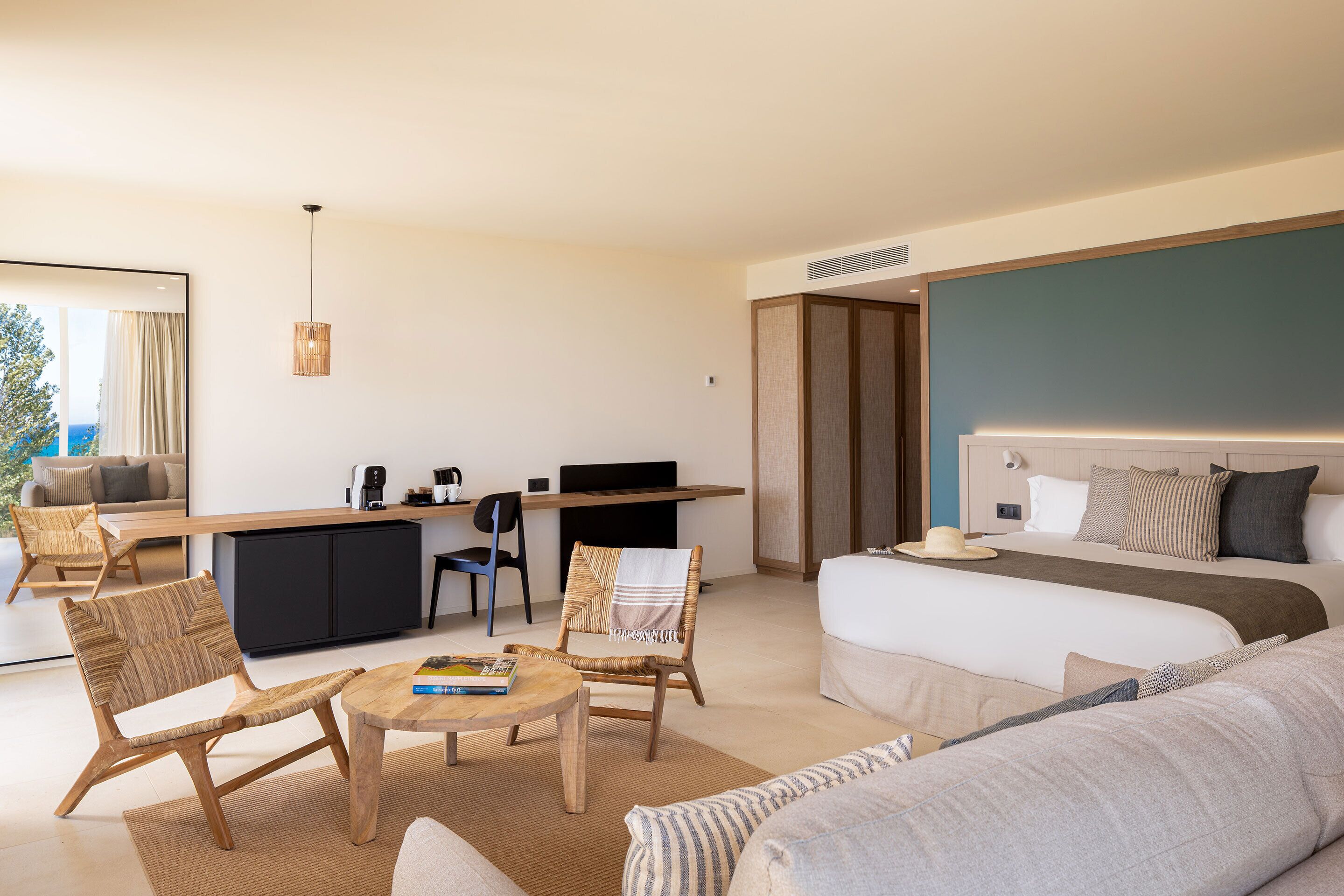 Een moderne hotelkamer met een groot bed, een slaapbank, een eettafel en een bureau met een computer.