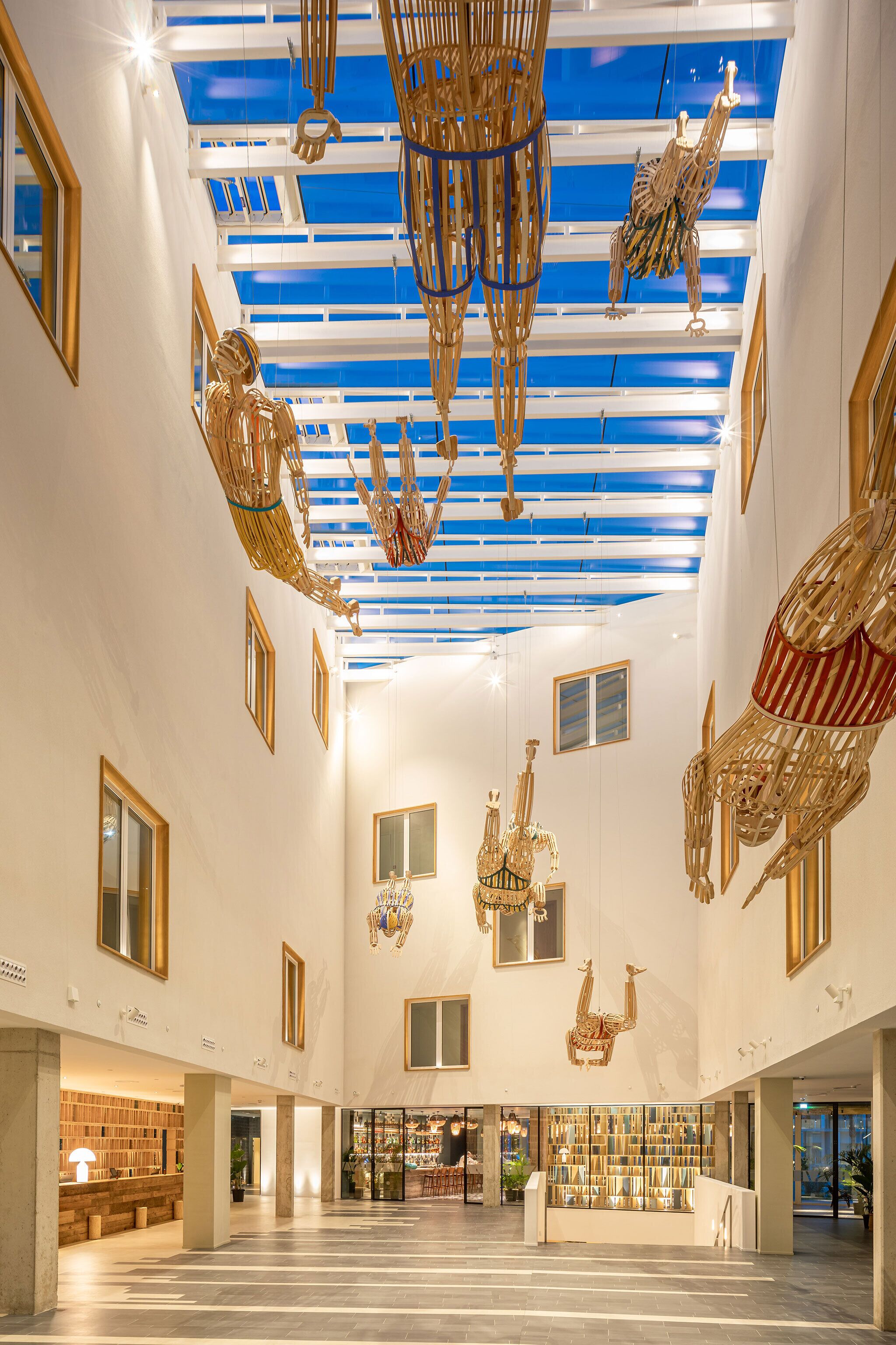 Een ruime lobby met hoge plafonds, grote ramen en moderne kroonluchters.