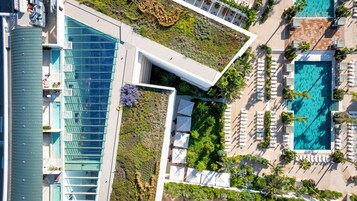 Un hotel moderno con piscina en la azotea, mobiliario de exterior y un jardín paisajístico.