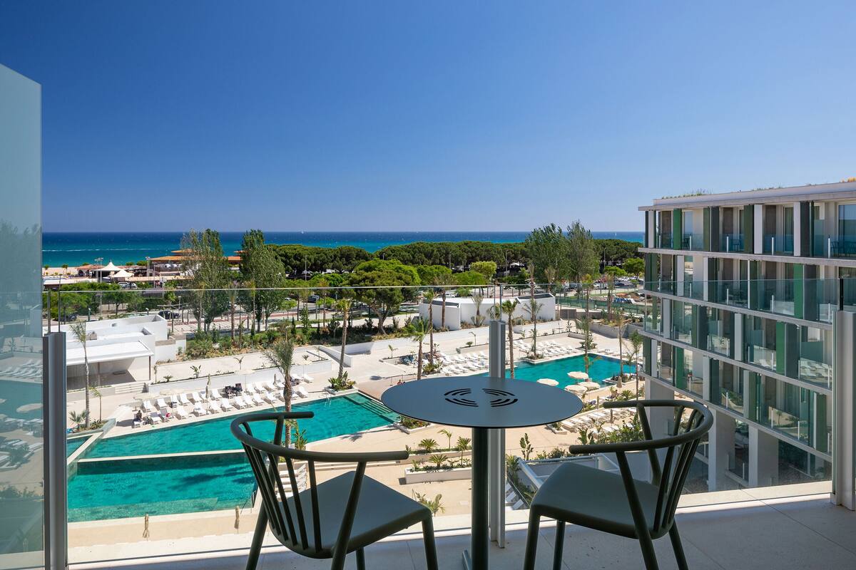 Ein Balkon mit Pool, Liegestühlen und Blick auf das Meer.