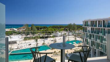 Ein Balkon mit Pool, Liegestühlen und Blick auf das Meer.