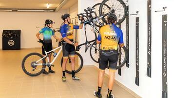 Interior de hotel con bicicletas colgadas en la pared, una exhibición temática de ciclismo y un cartel que promociona la hospitalidad para ciclistas.