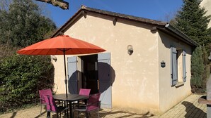 A small building with a tiled patio, a table with chairs, and an umbrella. - Independent cottage - private terrace - shared swimming pool (Simeyrols)