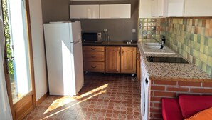 A compact kitchen with a refrigerator, microwave, sink, and wooden cabinets. - Independent cottage - private terrace - shared swimming pool (Simeyrols)