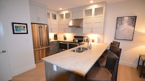 A modern kitchen with white cabinets, stainless steel appliances, and a central island with bar stools.