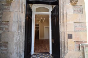 A hallway with a black door, a chandelier, and a patterned floor. - Rosedene Highland House - The Cottage Apartment 8 (Inverness)