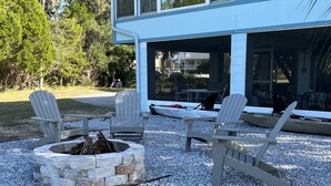 Un espacio al aire libre moderno con sillas Adirondack y un hogar de piedra.