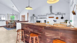 A modern kitchen with a wooden bar area, pendant lighting, and a dining area with a patterned rug. - Canyon Breeze I 3 Bedroom I Pet Friendly I Canyon Lake! (Canyon Lake)