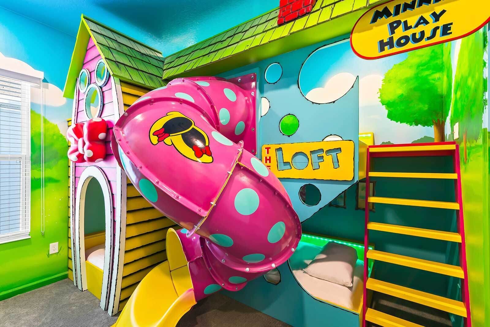 A colorful playhouse with a slide, a loft area, and a playhouse sign.