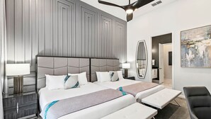 A modern hotel room with a large bed, two bedside tables, a ceiling fan, and a painting on the wall. - Fun Home w/ Trampoline RM, Pirate Theme BR, Arcade, Theater & Gym - Near Disney (Davenport)