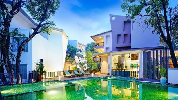 A modern hotel with a swimming pool, lounge chairs, and a well-maintained garden. - Amoravida By 7 Apple Resorts (Pernem)