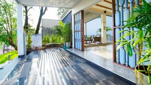 A spacious outdoor area with a tiled floor, potted plants, and a seating area with a table and chairs. - Amoravida By 7 Apple Resorts (Pernem)