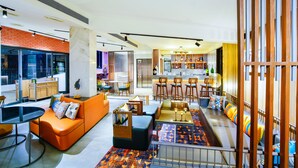 A modern living area with a sofa, ottoman, and a dining table. - Amoravida By 7 Apple Resorts (Pernem)