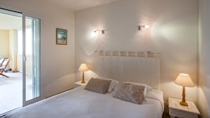Un dormitorio con una cama, dos lámparas de noche, una ventana y una puerta.