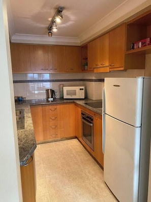 Una cucina compatta con mobili in legno, un forno a microonde, un frigorifero e una macchina da caffè.