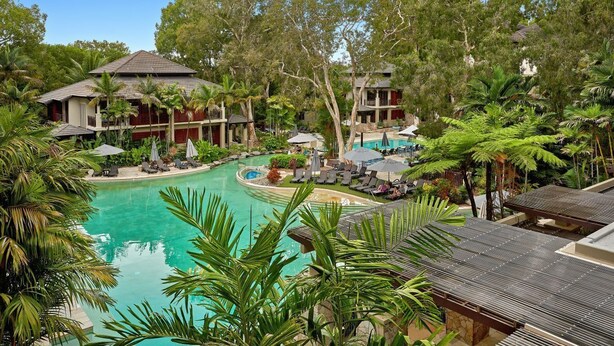 A resort with a central swimming pool, multiple guest villas, and lush tropical vegetation.