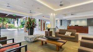 A modern lobby with a reception desk, seating area, and a large plant.
