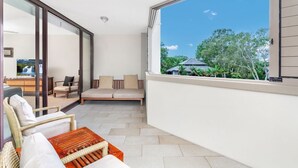 A balcony with a sofa, chairs, and a wooden table.