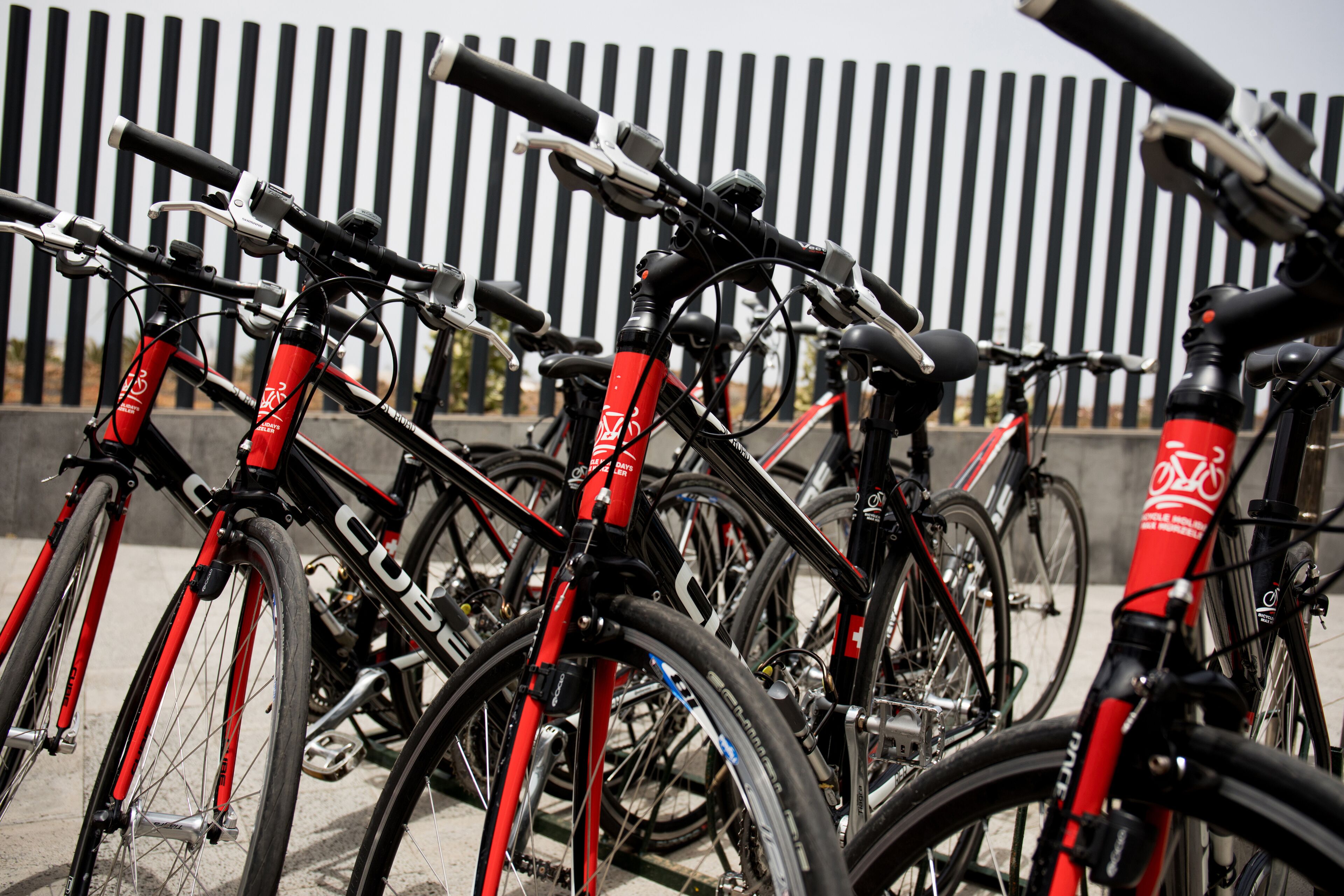 Varias bicicletas estacionadas frente a una cerca a rayas.