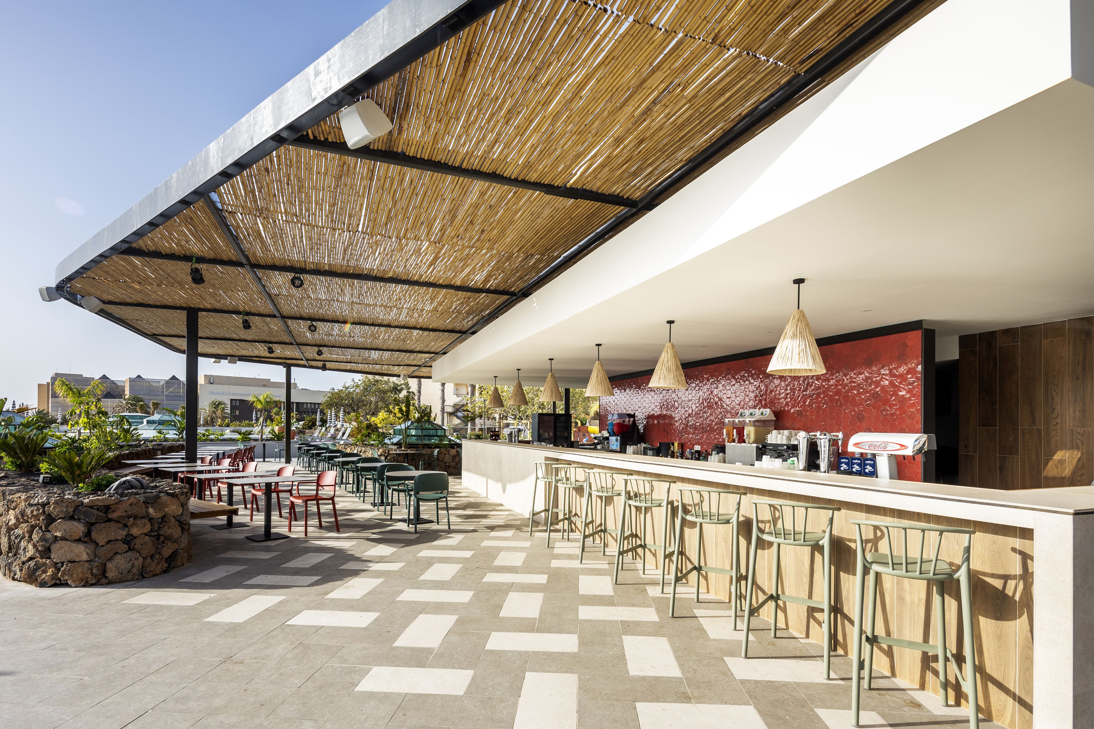 An outdoor bar area with a covered seating area, a counter with stools, and a view of the cityscape.