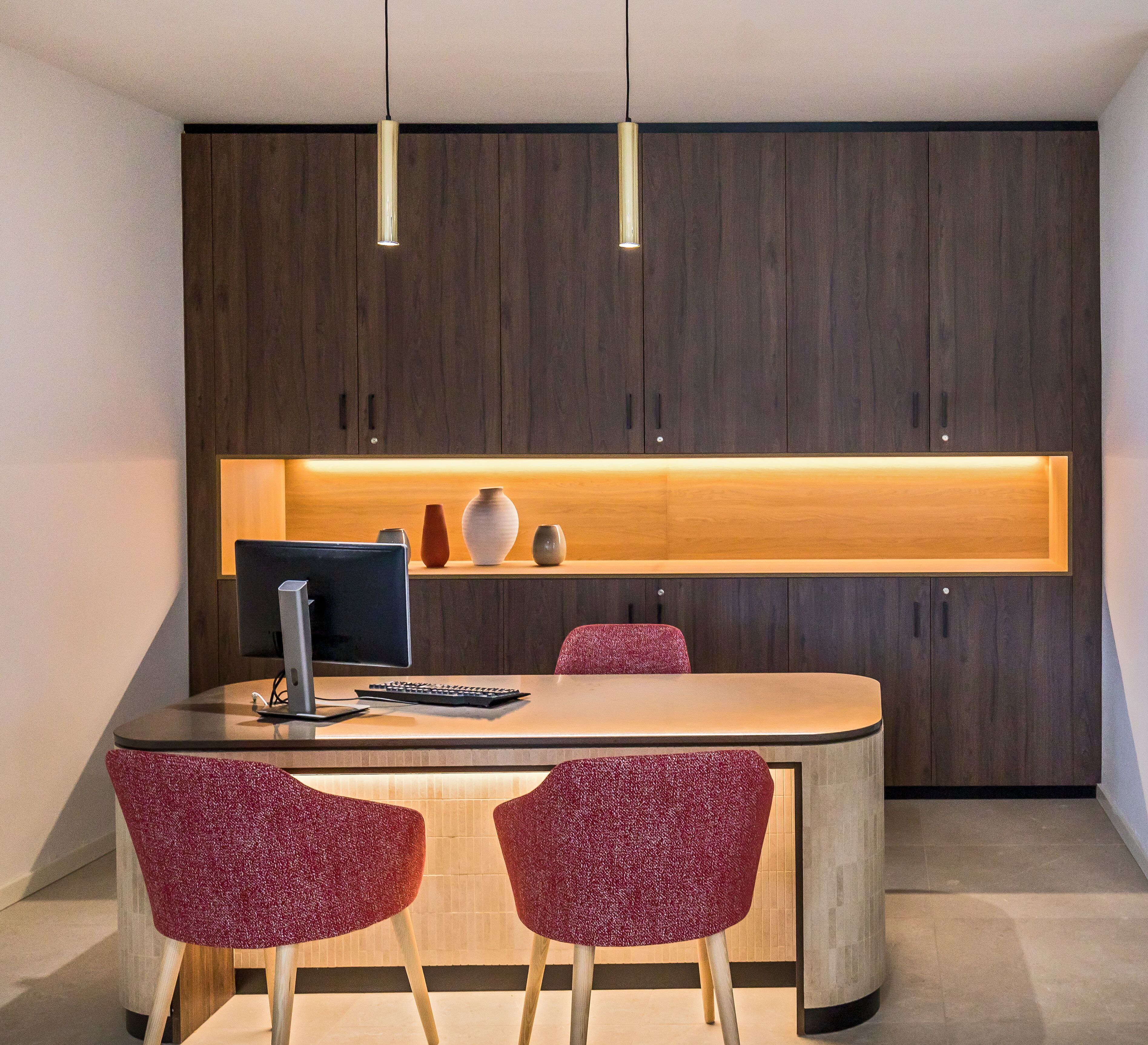 Una cocina moderna con una isla central, dos lámparas colgantes y un armario de madera arriba.