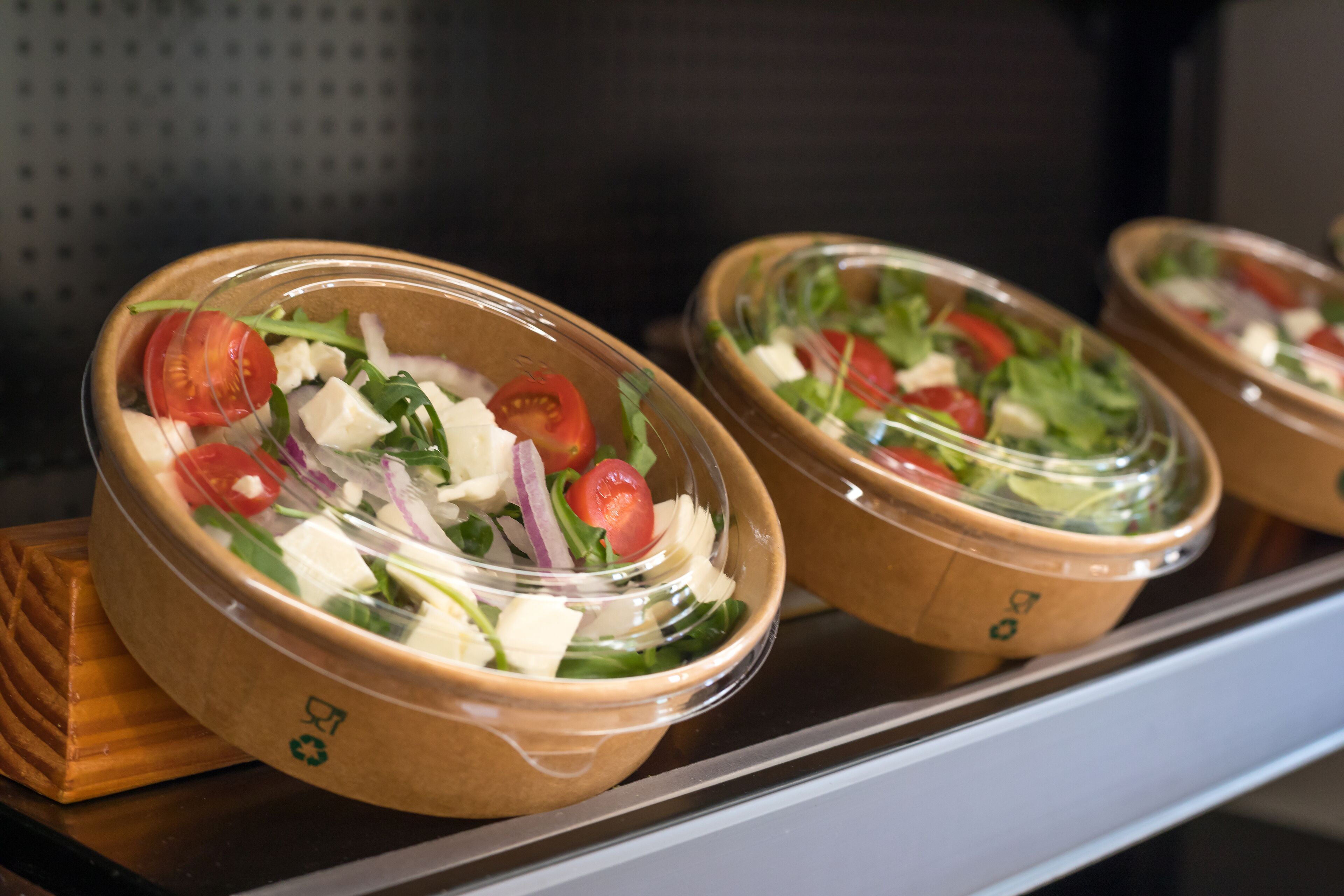 Three salad bowls with a lid on a shelf.