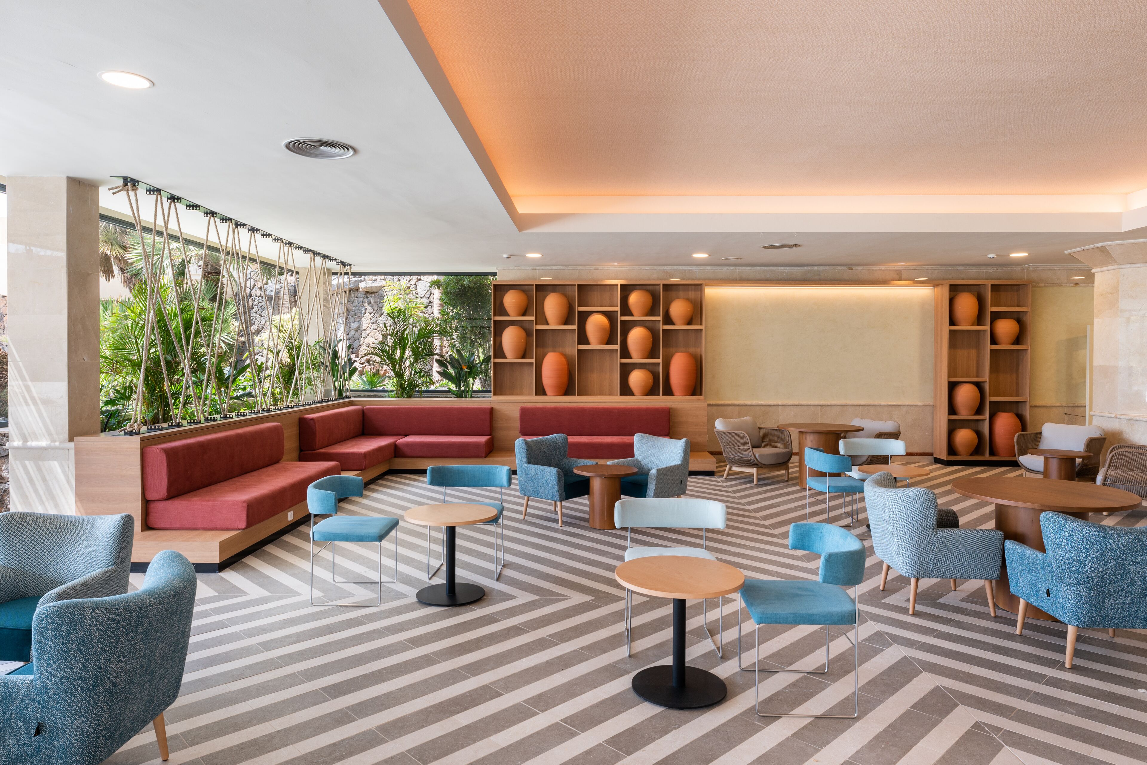 A modern lounge area with seating arrangements, tables, and decorative vases.