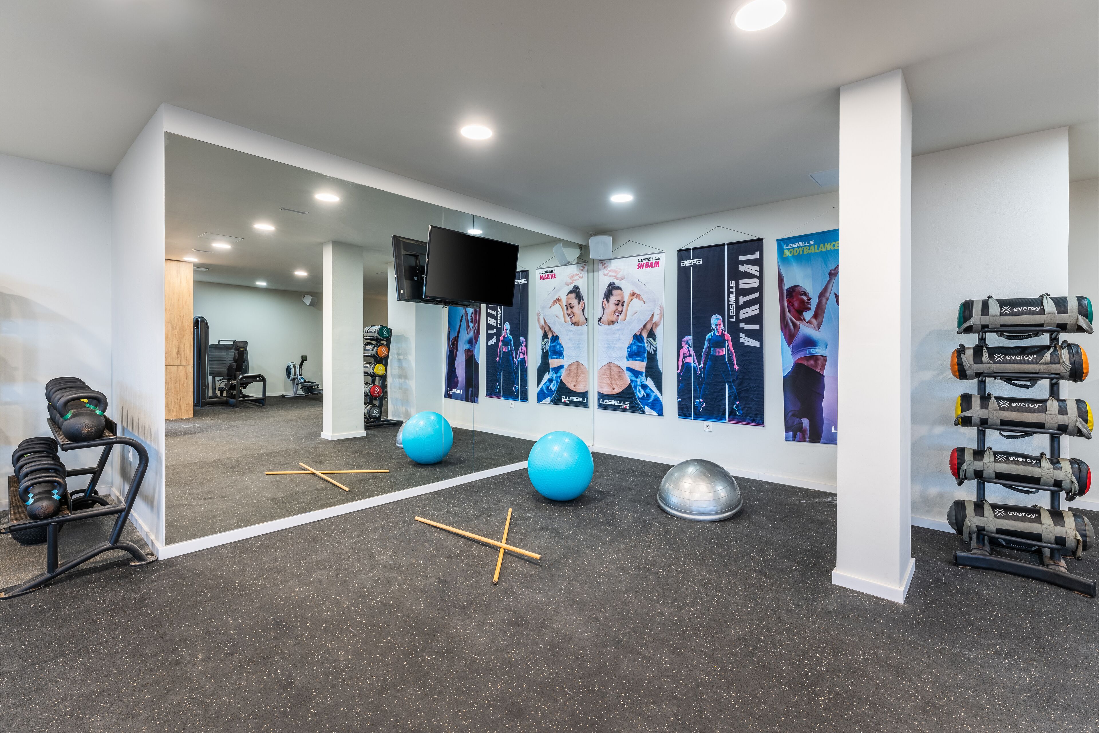 A modern gym with exercise equipment, posters, and a television.