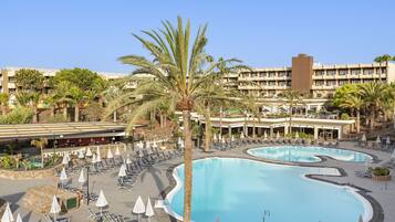 A resort with multiple swimming pools, sun loungers, and palm trees.