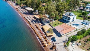 An aerial view of a coastal area with a beach, a row of sun loungers, and a building with a sign that reads "HUSK CAMPUS." - Kensington Green Marmaris (Marmaris)